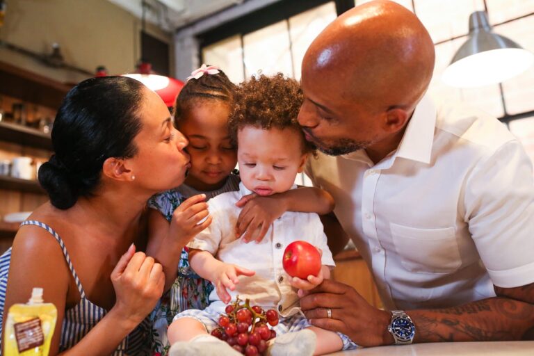 Família negra com duas crianças pequenas comendo frutas