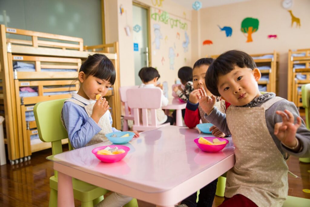 Foto de três crianças pequenas comendo na escola