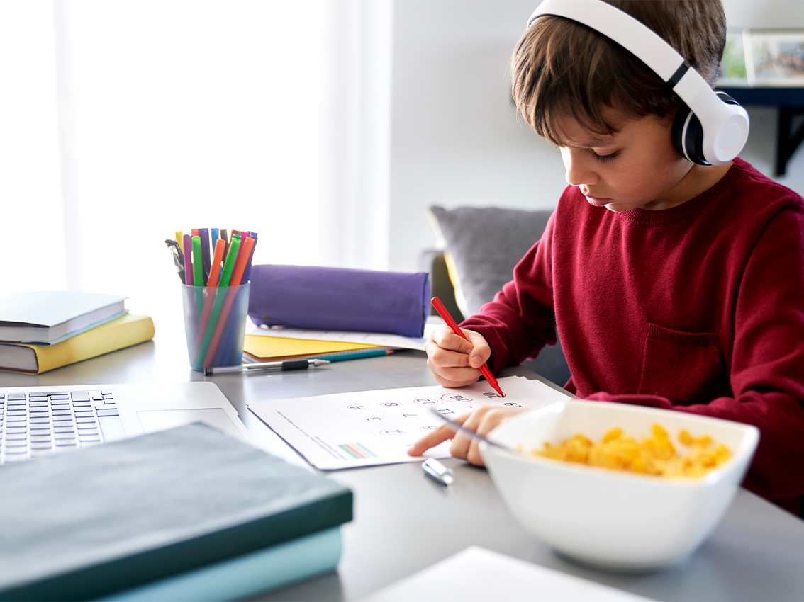 Criança estudando com alimentação escolar equilibrada.